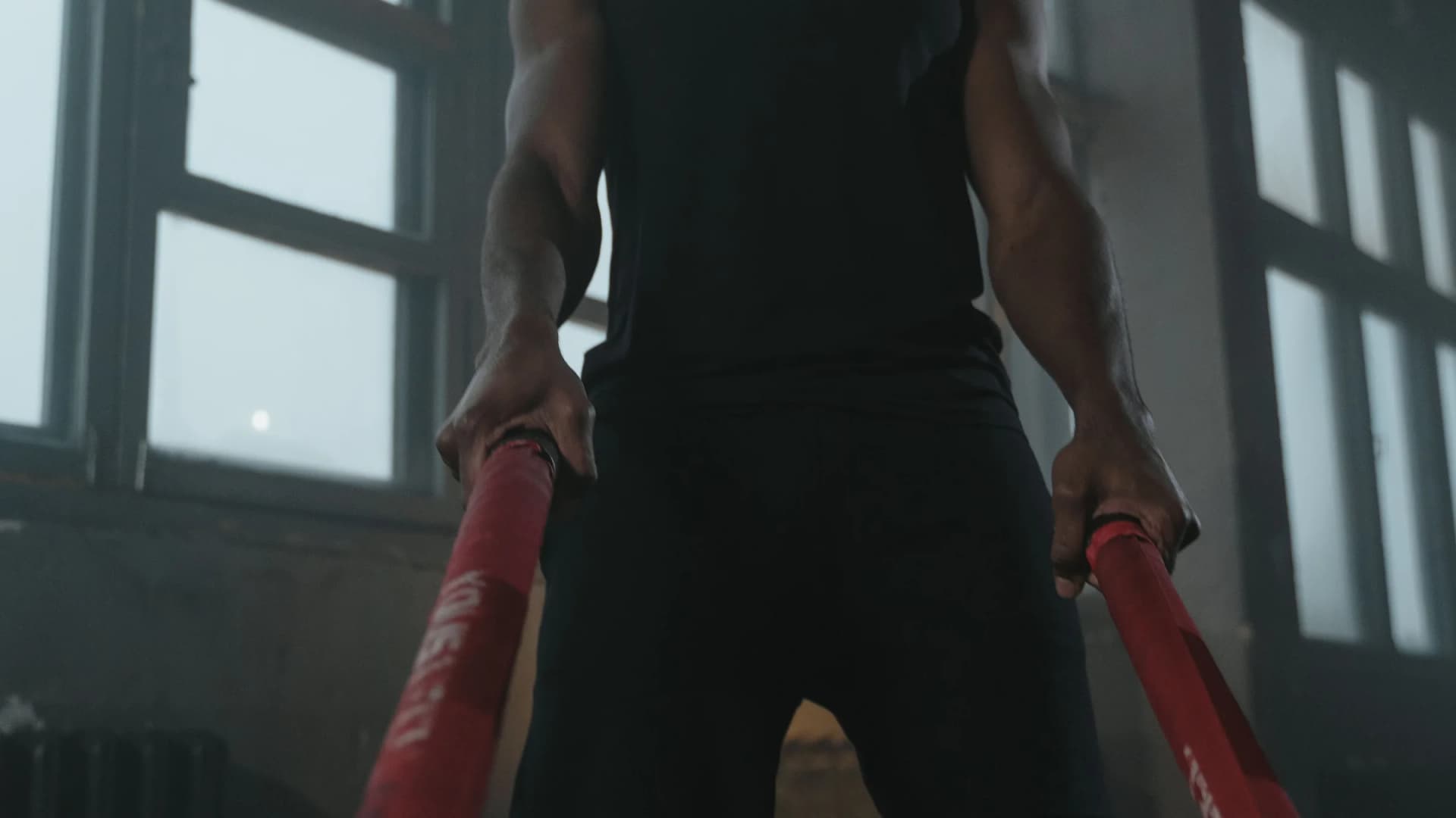 Persona entrenando con cuerdas de batalla en un gimnasio