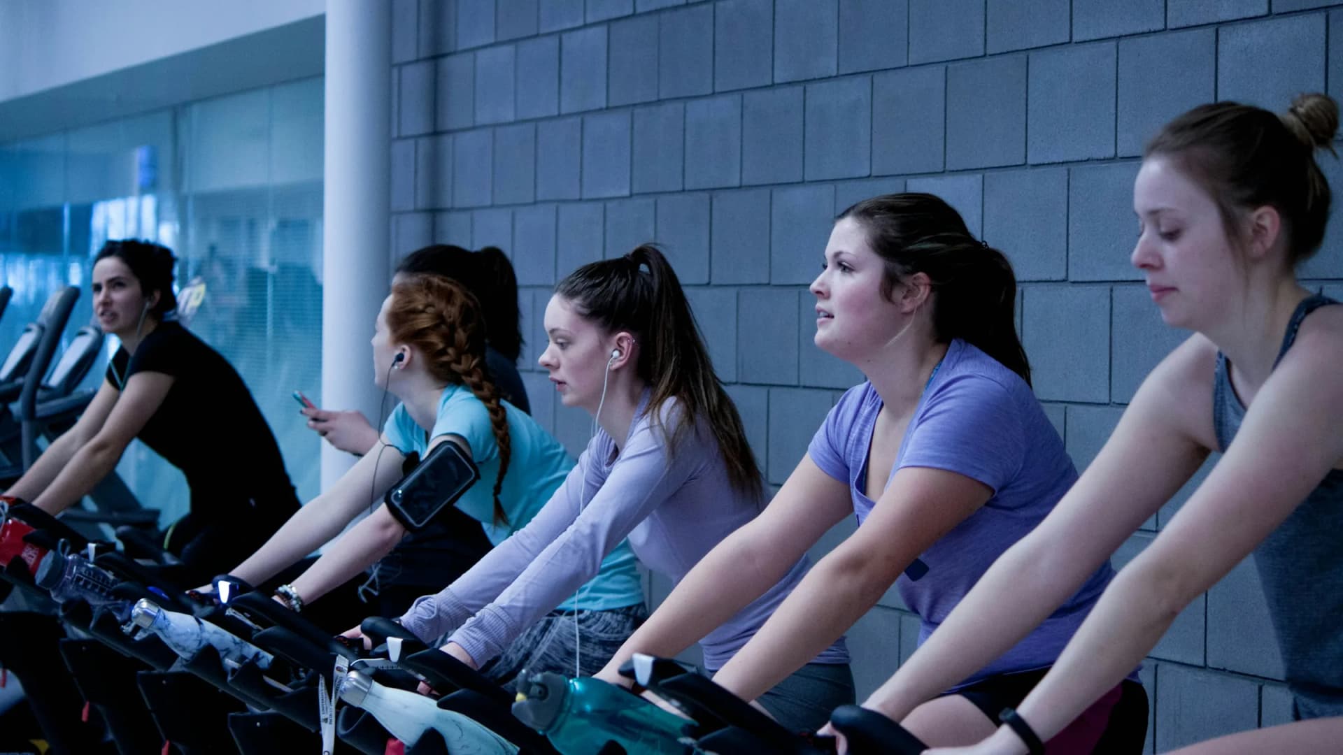 Clase de indoor cycling con personas pedaleando en bicicletas estáticas